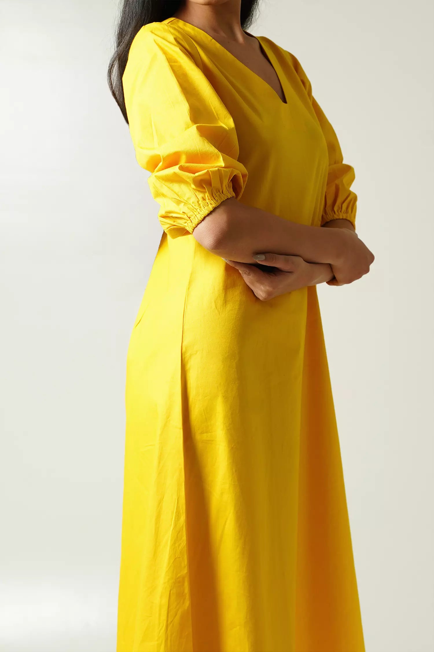 Yellow dress with puff sleeves worn by a girl on a white background