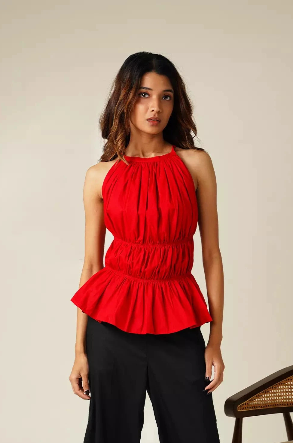 from view of woman wearing odd lama red sleeveless tiered top with peplum bottom against plain background