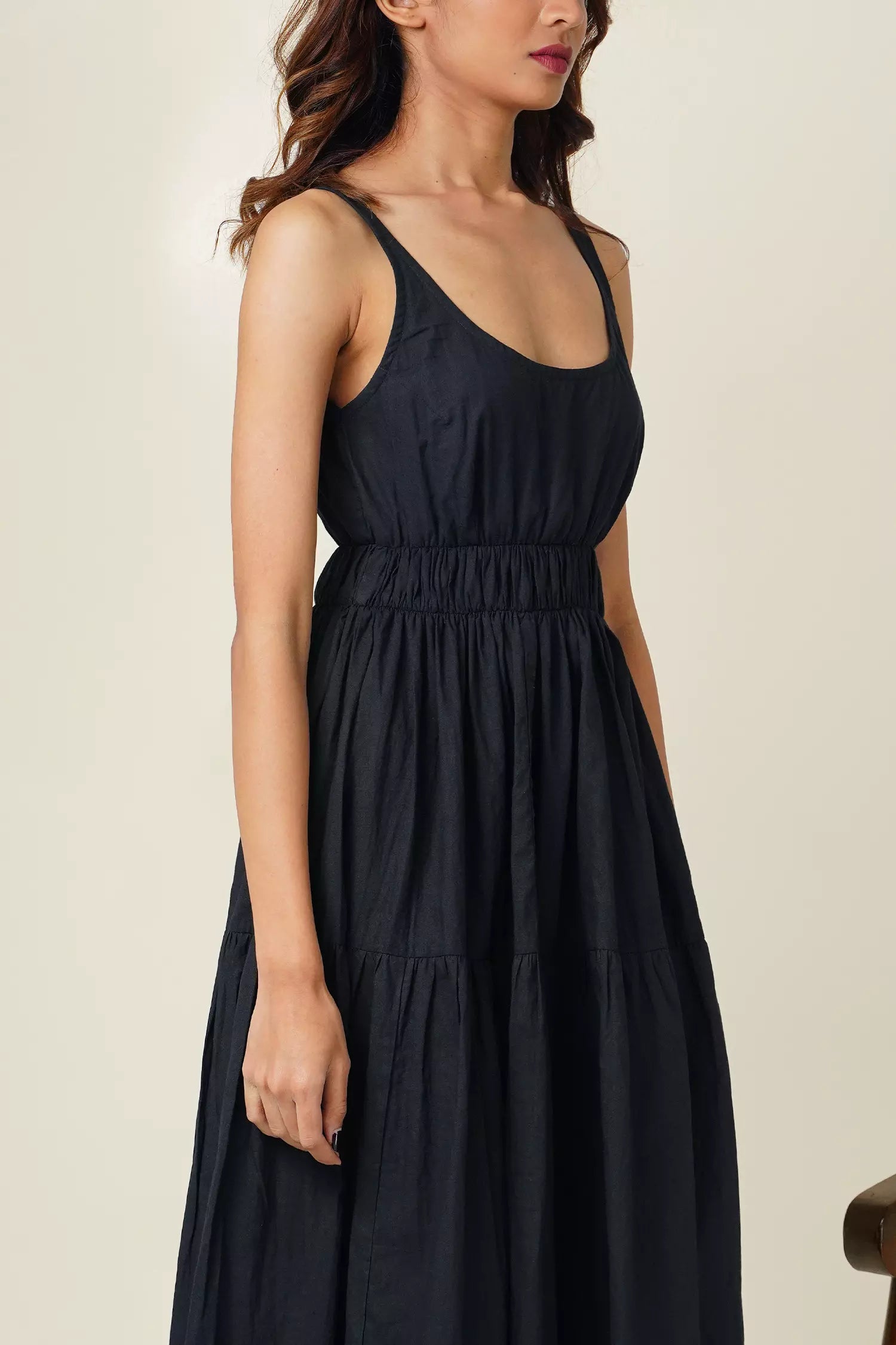 close up side view of woman wearing the odd lama ankle length black tiered dress in pure cotton