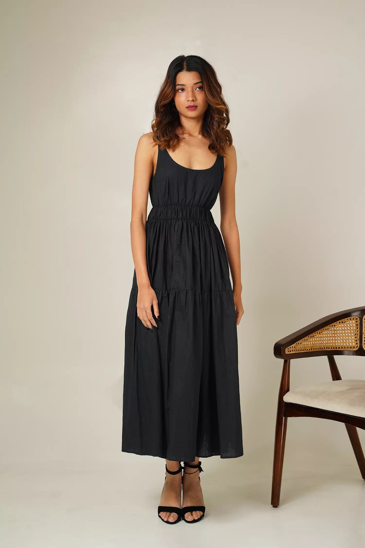 Front view of woman wearing the odd lama ankle length black tiered dress in pure cotton